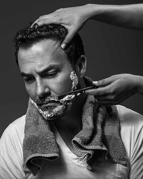 Acquiescence woman shaving man with straight razor